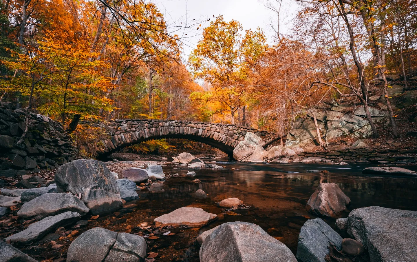 Autumn trees surround the stone arch of Boulder Bridge above Rock Creek.