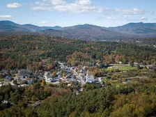 Aerial view of Stowe’s white church steeple, village streets and autumn hills in Vermont.