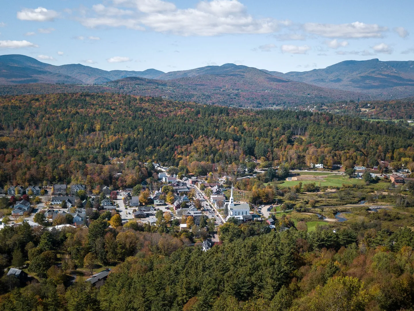 Aerial view of Stowe’s white church steeple, village streets and autumn hills in Vermont.